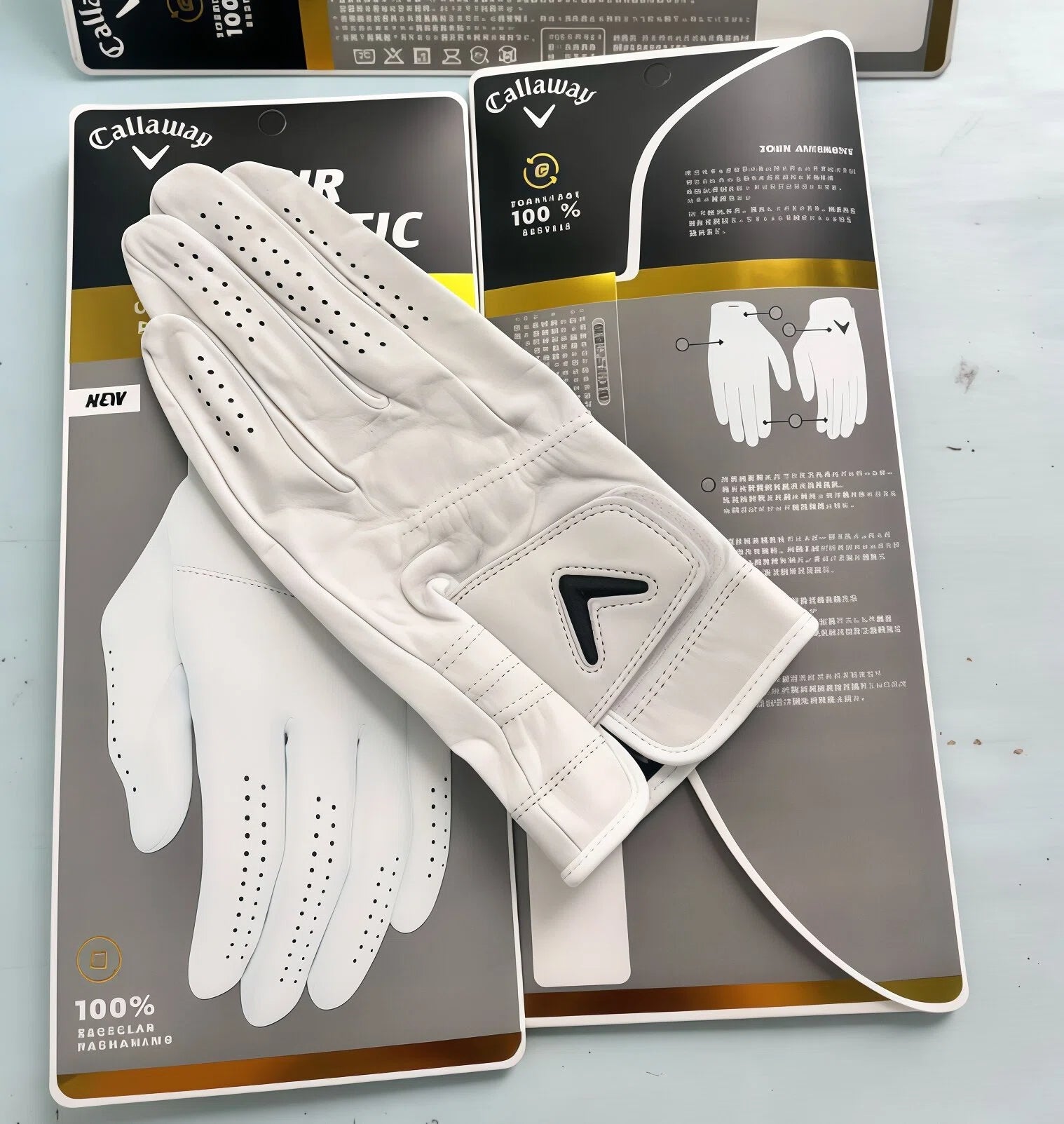 Top-down view of the Callaway Tour Authentic leather golf glove resting on retail packaging, displaying the reinforced stitching and classic Callaway chevron logo.