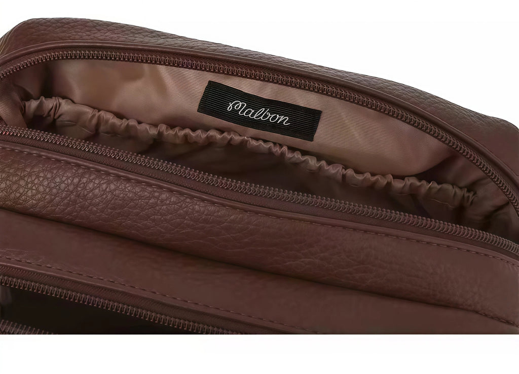 Close-up of the Malbon clutch interior showing soft brown satin lining and a black woven label with the "Malbon" script logo. High-quality craftsmanship ensures durability and brand authenticity.
