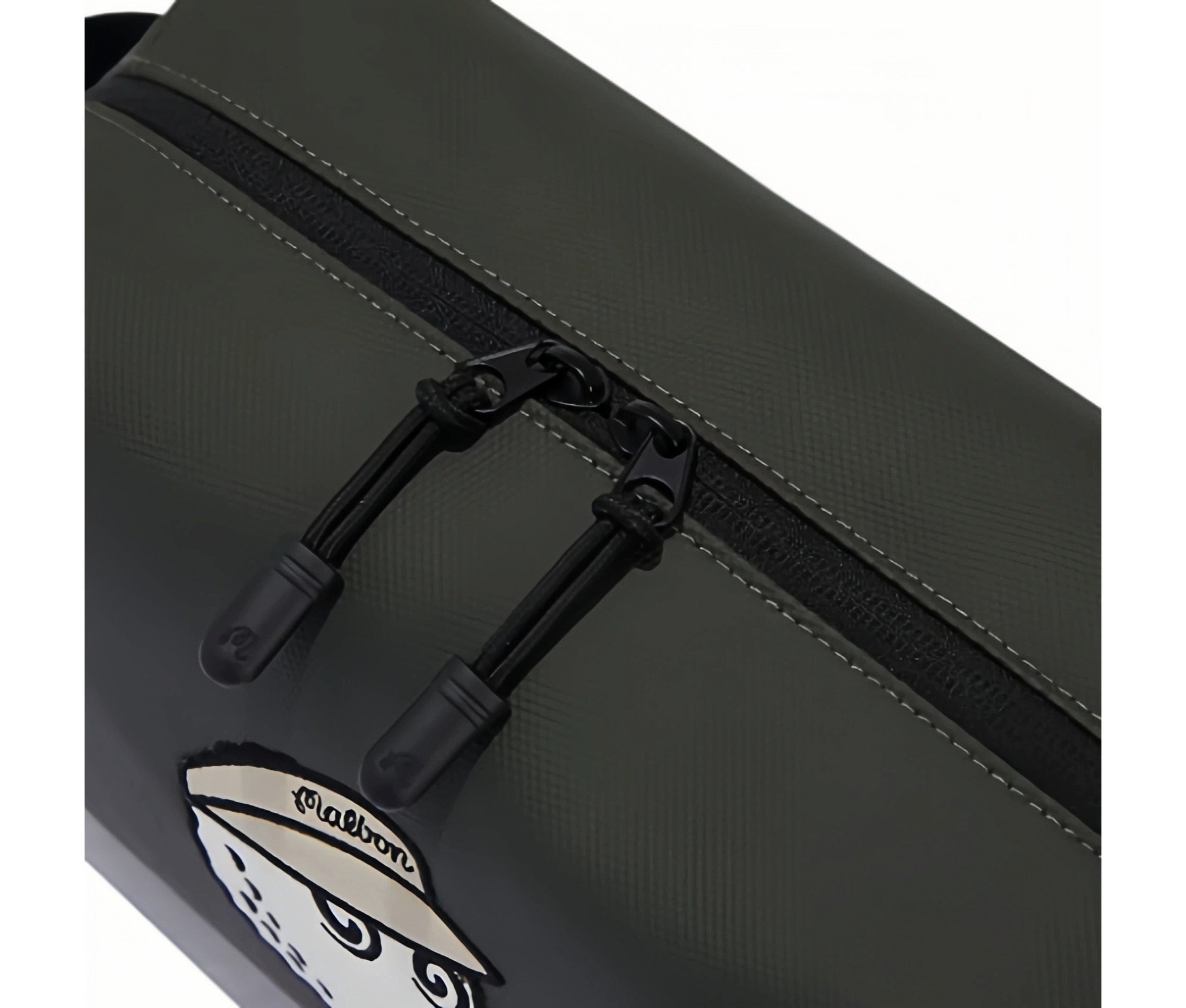 Close-up of Malbon Golf mini handbag top zipper featuring two black zip pulls with embossed "M" logo, smooth texture, and precise stitching along the seam