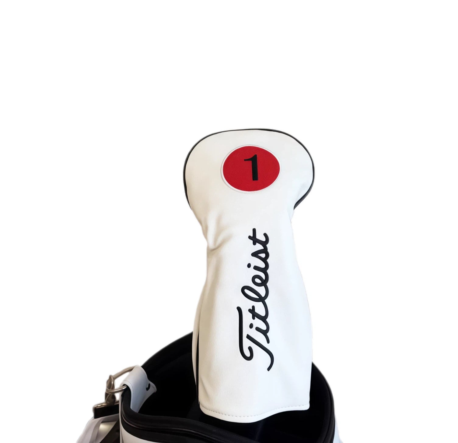 Close-up of a white Titleist-style driver headcover with a red circular "1" patch and black cursive "Titleist" branding, neatly placed in a golf bag — ideal for protecting your driver with classic style and durability.
