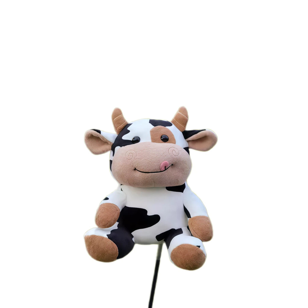 Cute black and white cow plush golf driver headcover fitted to a club shaft, tan horns, ears and smiling muzzle